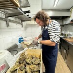 Un cocinero cocinando ostras con un guante especial.