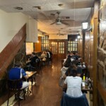 Sala de comedor de restaurante Shimoji, los clientes sentados.